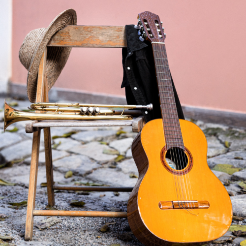 A acoustic guitar and brass instrument resting on a wooden chair